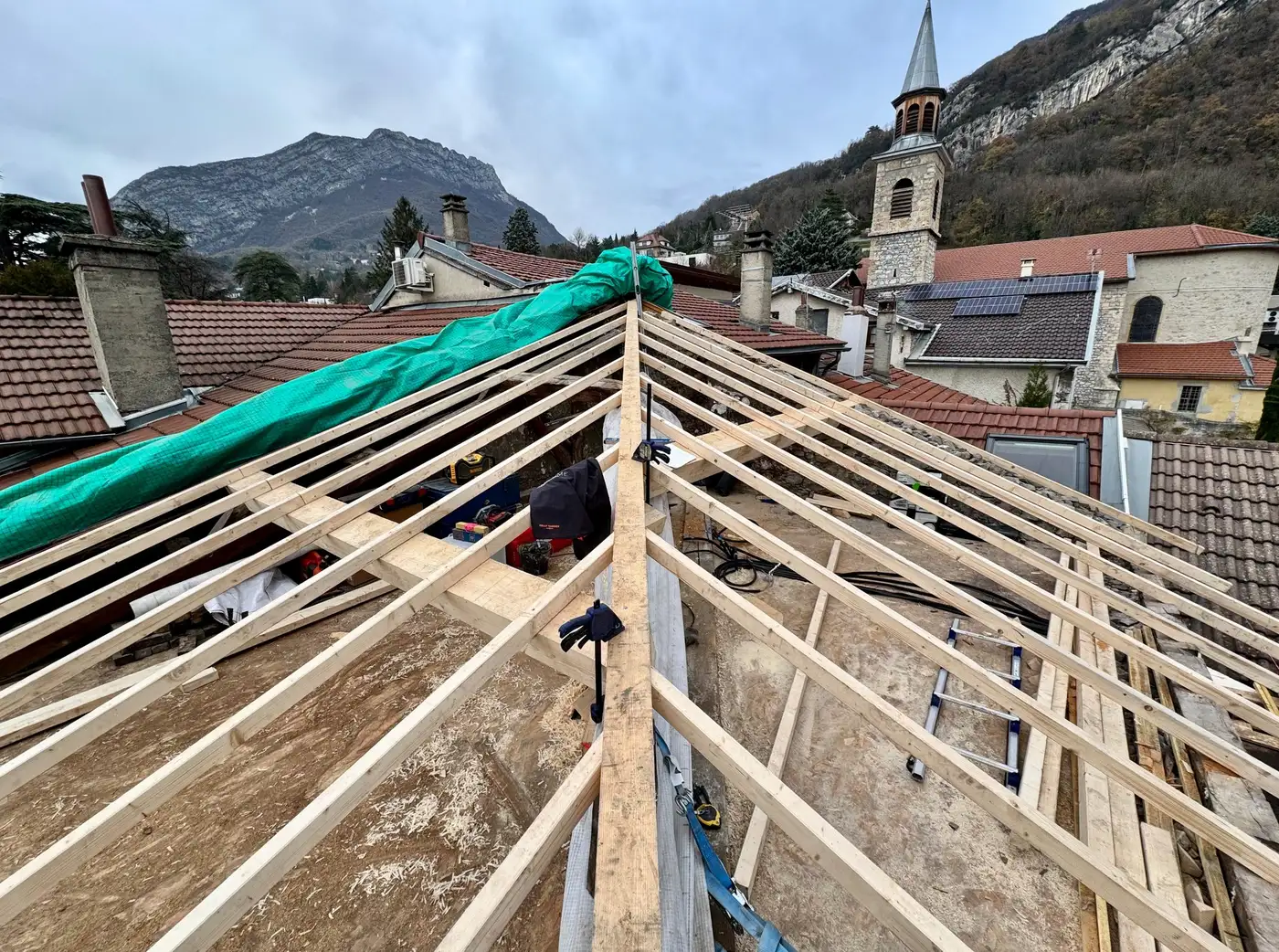 Charpente neuve montée sur un bâti de village, arêtier et chevrons posés avant couverture.