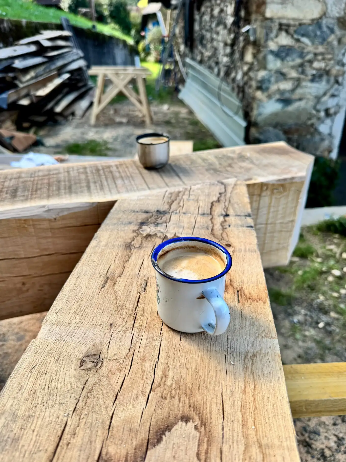 Deux tasses à café émaillées posées sur une poutre de chêne fraîchement taillée.
